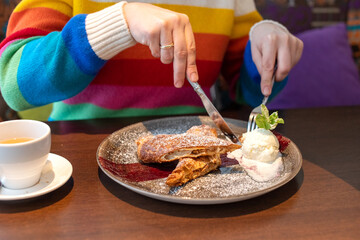 A woman in a bright sweater ordered a strudel with apples and ice cream