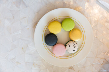 Brown, beige, green and cream colored French macarons on plate