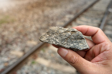 Raw specimen of granite igneous rock stone on Geologist's hand. The paving stones are used to...