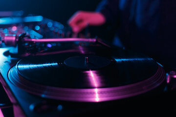 DJ turntable player playing vinyl record on techno party in dark night club