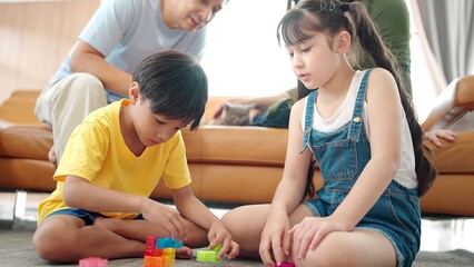 Asian family spending time together on holiday in living room at home. Activity relationship. Young two kids daughter and son play with toys in different colors