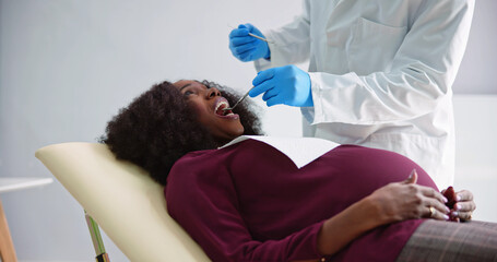 Dentist Treating Teeth Of Young Pregnant Woman Patient Lying