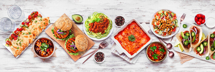 Healthy plant based vegetarian meal table scene. Overhead view on a white wood banner background....