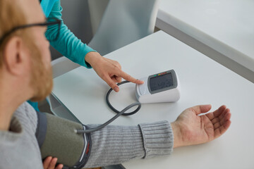 Nurse or doctor uses a tonometer to measure the blood pressure of a senior man patient with hypertension. Medicine, high pressure, old age, medical check-up, and treatment concepts