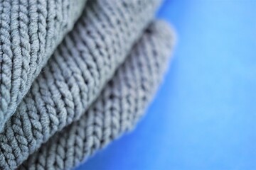 Cozy gray knitted sweater on blue table, copy space