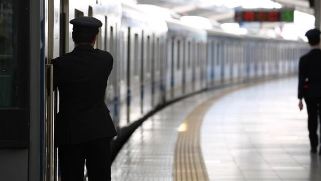 People are Walking on Platform in Metro Train Station Platform in Tokyo. Underground Metro Train During Rush Hour. Conductor is Checking Status