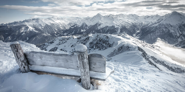 Panoramabild einer Holzbank mit Aussicht über die Alpen
