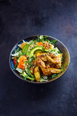 Traditionaler deutscher Eisberg und italienischer Rucola Salat serviert mit Hähnchen, Avocado und Gemüse mit würziger süß sauer Curry Sauce als close-up auf einer Schale mit Textfreiraum