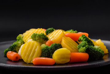 Delicious fresh vegetables steamed carrots, broccoli, cauliflower on a black plate