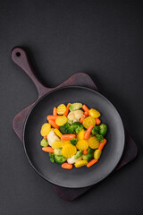 Delicious fresh vegetables steamed carrots, broccoli, cauliflower on a black plate