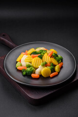 Delicious fresh vegetables steamed carrots, broccoli, cauliflower on a black plate