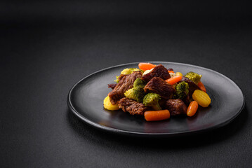 Delicious fresh beef and vegetables carrots, broccoli, cauliflower on a black plate
