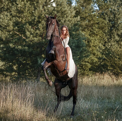 Beautiful girl riding a horse rearing up - 575415036