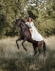 Beautiful girl riding a horse rearing up - 575415054