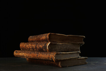 Old books. Four volumes of old books on a black background. The concept of knowledge and collecting. The old library.Copy space.