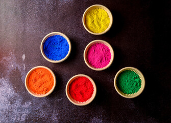 top view of colorful traditional holi powder in bowls isolated on dark background.Space for text . happy holi.Concept Indian color festival called Holi