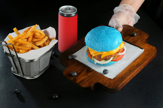 delicious blue color venison burger served on wooden tray black background with soft drink and Potato Fries dear meat
