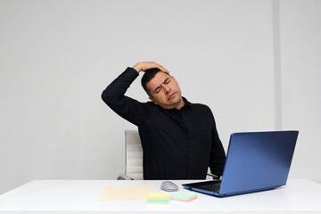 Latino adult man works in his office with his laptop, his head, neck, and back, cervical, lumbar...