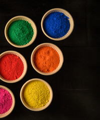 top view of colorful traditional holi powder in bowls isolated on dark background.Space for text . happy holi.Concept Indian color festival called Holi