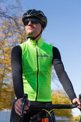 A man in clothes stands with a bicycle on an autumn sunny day. Cyclist in the park.
