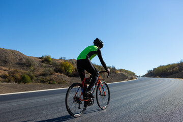 Cyclist riding bicycle on road against clear sky