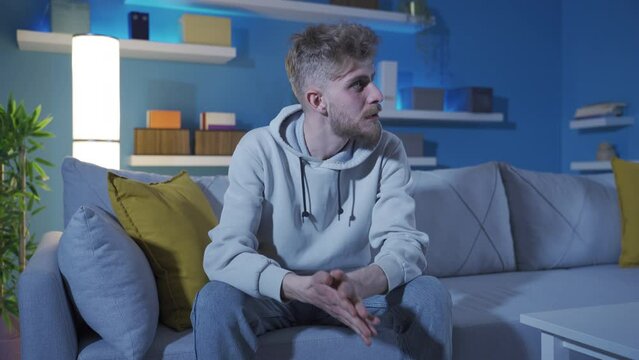 Aggressive and obsessive neurotic young man angry at home.
The bored young man harbors a grudge, wants revenge, cannot control his anger, does not want to become a loser.
