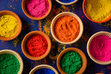 top view of colorful traditional holi powder in bowls isolated on dark background.Space for text . happy holi.Concept Indian color festival called Holi