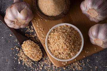 Dry garlic granules. Spice garlic. Dry garlic powder in a wooden bowl and spoon.