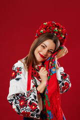 Portrait of ukrainian woman in traditional ethnic clothing and floral red wreath with handkerchief on viva magenta studio background. Ukrainian national embroidered dress call vyshyvanka