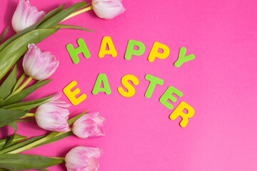 Fototapeta na wymiar beautiful tulips flowers and word Happy Easter on pink background