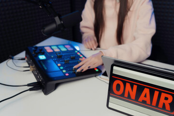 From above anonymous female adjusting fader on mixing console while sitting at table and recording podcast in studio