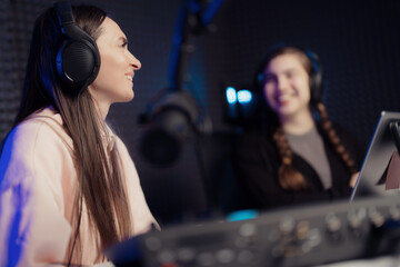 Female host and guest sitting at table with equipment while broadcasting radio program in recording studio