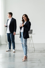 Obraz premium The team in the office. A woman with a cup of coffee in her hands on the background of the office.