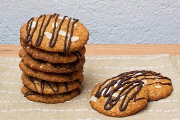 Galletas de avena y chocolate apiladas sobre paño de cocina y fondo blanco con textura. 