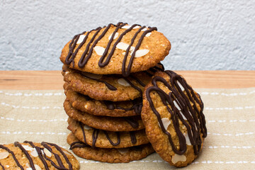 Galletas de avena y chocolate apiladas sobre paño de cocina y fondo blanco con textura. 