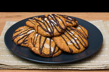 Galletas de avena y chocolate en plato oscuro y mesa de madera.