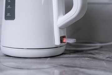 A woman draws water into an electric kettle in the background of the kitchen. It's time for...