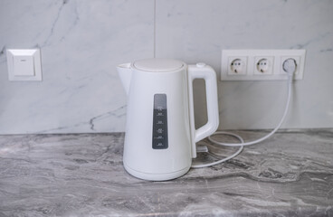 A woman draws water into an electric kettle in the background of the kitchen. It's time for...