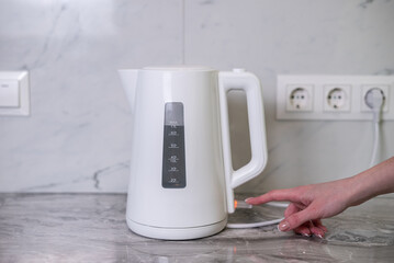 A woman draws water into an electric kettle in the background of the kitchen. It's time for...
