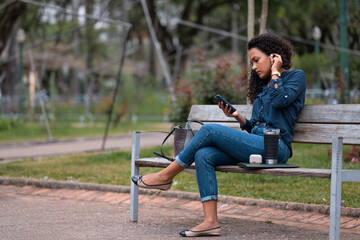 Young African American businesswoman smiling and looking at her smartphone while adjusting her...