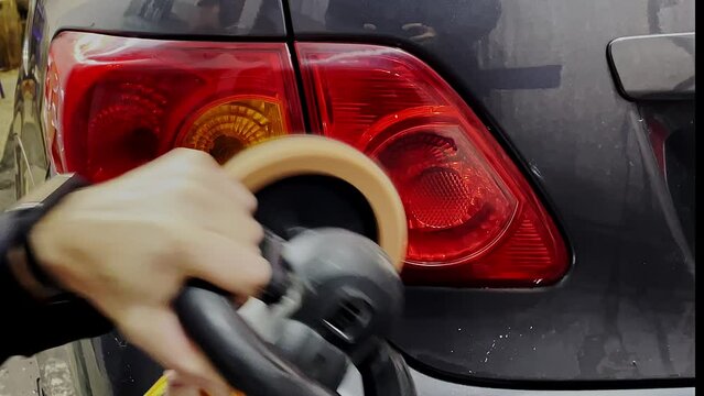 Caucasian man polishing stoplights of a car using yellow polisher.