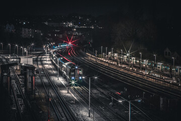 Train tracks at night by the platform with train approaching