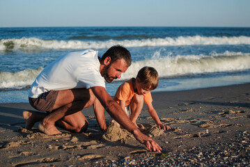 dad and son spend time together on the ocean playing near the water