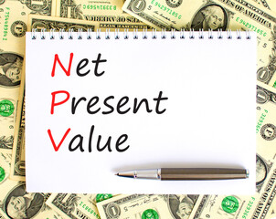 NPV net present value symbol. Concept words NPV net present value on white note on a beautiful background from dollar bills. Pen. Business and NPV net present value concept. Copy space.