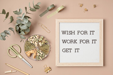 Flatlay of letter board with motivational quote. Office supplies made of recycled materials on beige background.