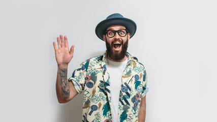 Portrait of a cute smiling hipster guy with a beard in glasses, a hat and a Hawaiian shirt. Crazy emotions. Discounts, sales, seasonal sales. Colorful summer concept.