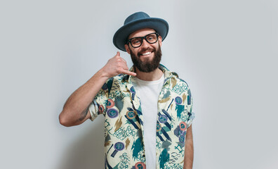 Portrait of a cute smiling hipster guy with a beard in glasses, a hat and a Hawaiian shirt. Crazy emotions. Discounts, sales, seasonal sales. Colorful summer concept.