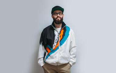 Portrait of a stylish hipster model guy with a beard in glasses, a cap and a vintage tracksuit from...