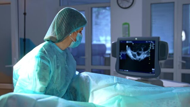 Obstetrician checking the patient on ultrasound machine. Doctor looks attentively at the screen. IVF procedure in the hospital.