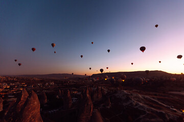 Flying hot air balloons rise in sunrise Cappadocia. Goreme National Park Turkey.